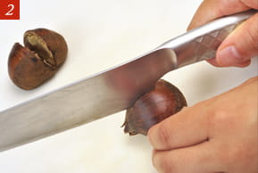 ２　包丁で栗を切っている写真。