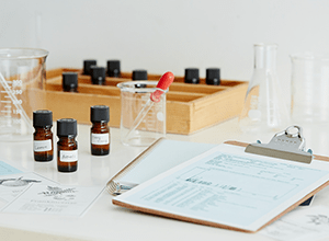 机の上に精油、ビーカー、スポイトが乗っている写真