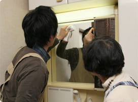 洗面所の鏡を拭く依藤と前さん。