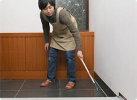 玄関を掃く依藤。