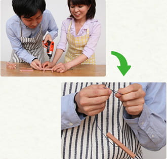 レッドシダーを加工する吉島先生と依藤　ヒモを結んでいる写真